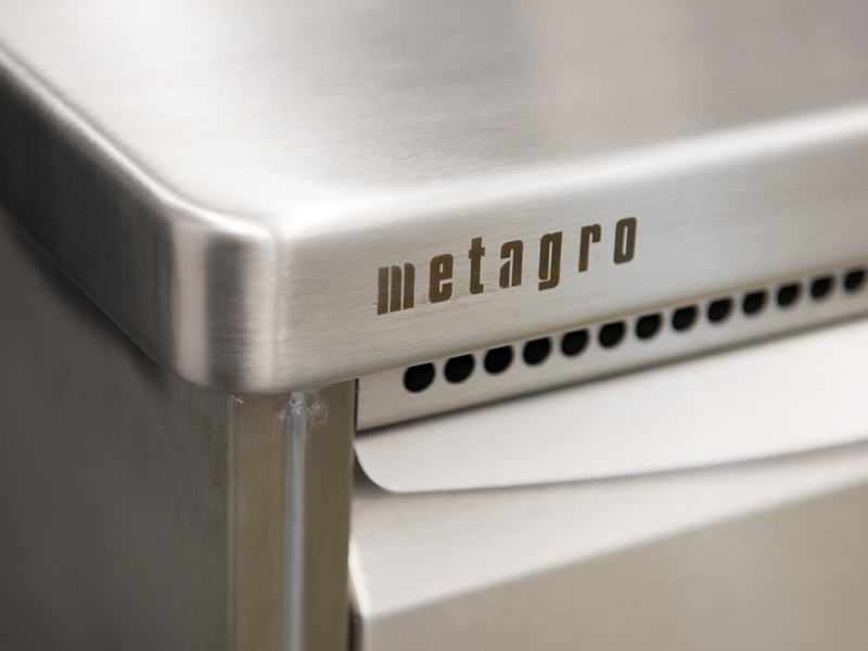 Detail-Aufnahme von Arbeitsplatte mit gerundetem Eck und gelochtem Blech bei Brotlade (Edelstahl)